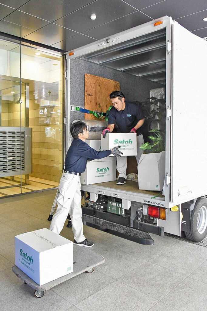 トラックから荷物を2人で運び出すサトー運送の作業員。