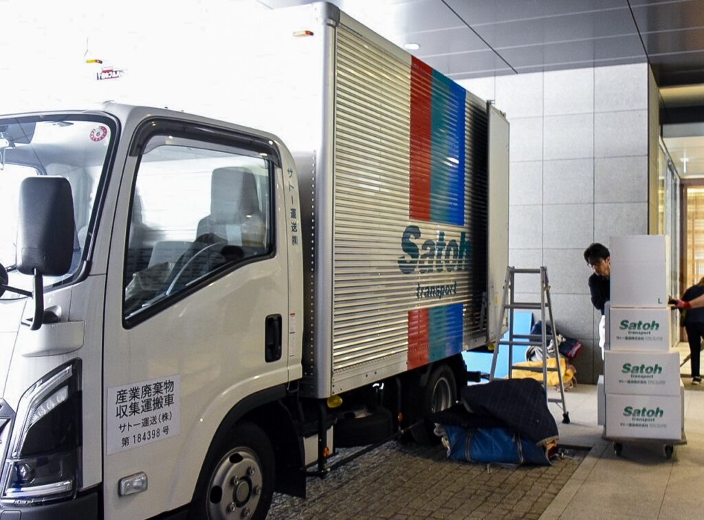 トラックからおろした荷物を台車で運ぶサトー運送の作業員