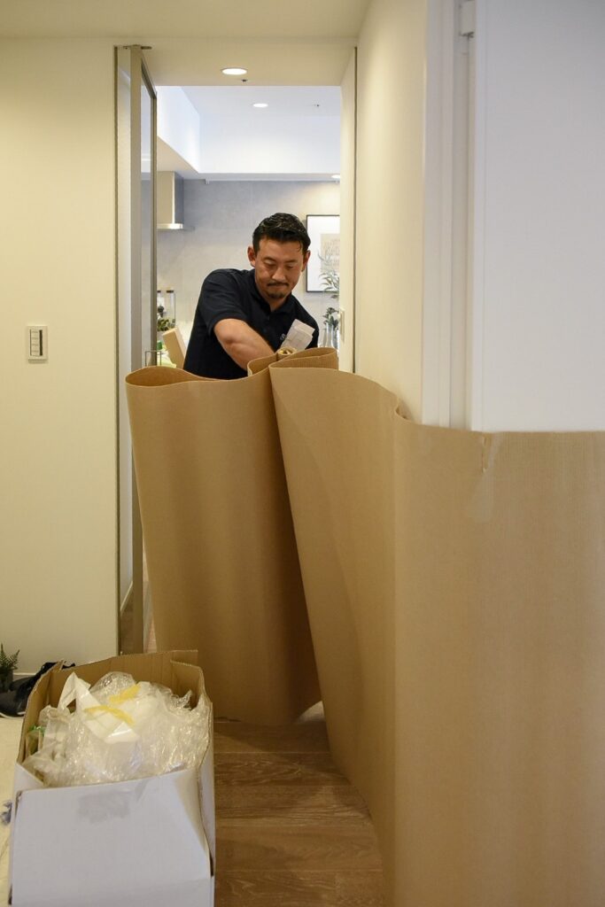 モデルルームの部屋の中を養生するサトー運送の作業員。