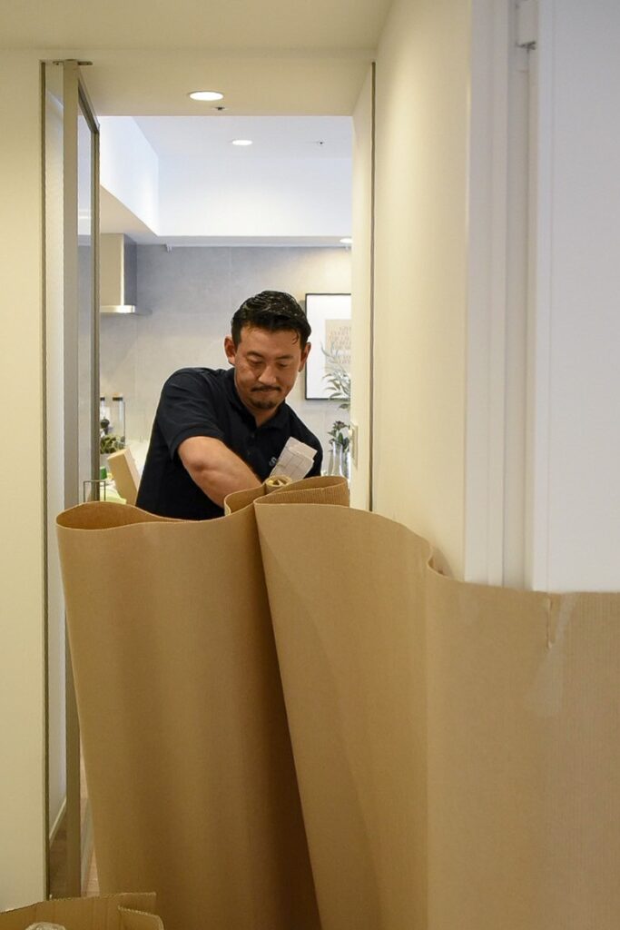 モデルルームの部屋の中を養生するサトー運送の作業員。
