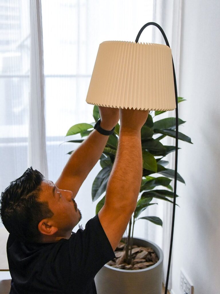 フロアランプに電球を設置するサトー運送の作業員。